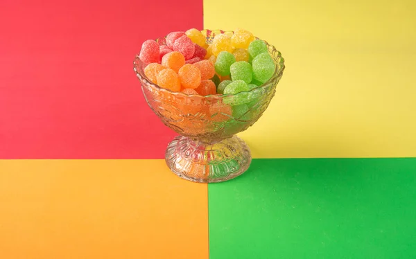 Gummy candy, arrangement of gummy candy seen from above in a glass jar on a colored surface.