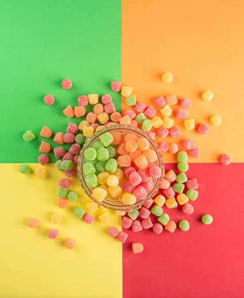 Gummy candy, arrangement of gummy candy seen from above in a glass jar and spread on the table on a colored surface.