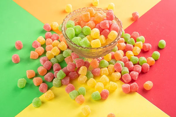 Gummy candy, arrangement of gummy candy seen from above in a glass jar and spread on the table on a colored surface.