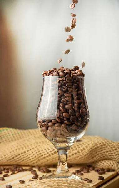 Coffee, coffee falling into a cup on a rustic wooden surface, rustic fabric and gray background, selective focus.