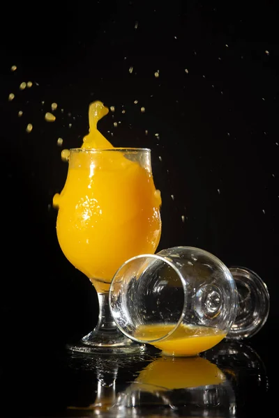 Orange juice, splash in beautiful glasses of orange juice, black background, selective focus.