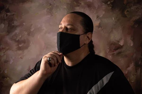 Portrait of brazilian man wearing mask against covid-19, abstract background, selective focus