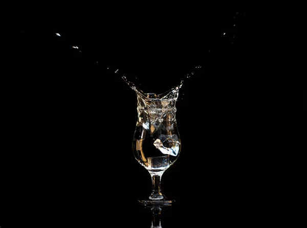 Splash with cup and water on black background, selective focus.