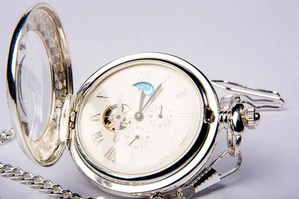 Antique watch, beautiful details of an old pocket watch on white surface, selective focus.