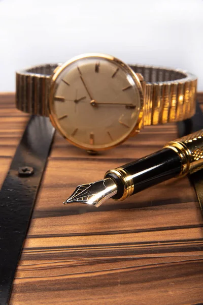 Fountain pen, beautiful fountain pen in detail on rustic wood along with an old clock, selective focus.