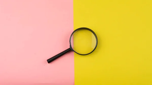 黄色とピンクの背景に虫眼鏡の選択的な焦点 — ストック写真