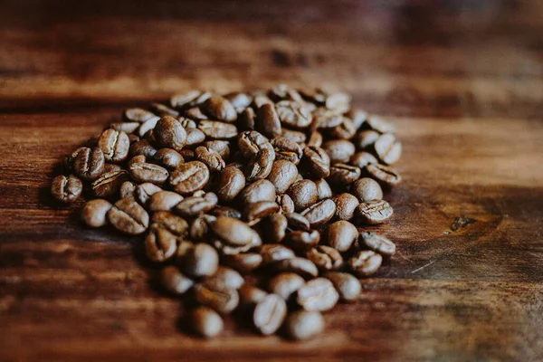 Coffee beans in the hands of heart shaped on wood table dark style and vintage