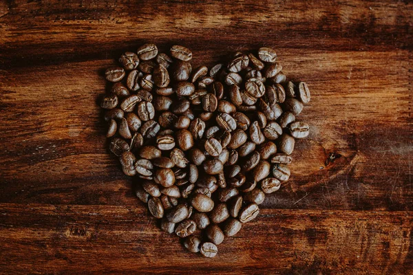 Coffee beans in the hands of heart shaped on wood table dark style and vintage