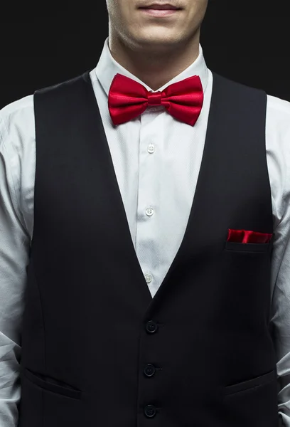 Bonito elegante jovem homem de moda em preto traje clássico terno, camisa branca e laço vermelho — Fotografia de Stock