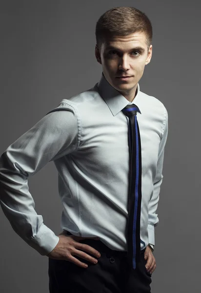 Retrato de homem jovem em uma camisa clássica e gravata com linha azul posando em um fundo cinza. Conceito de bom empresário — Fotografia de Stock