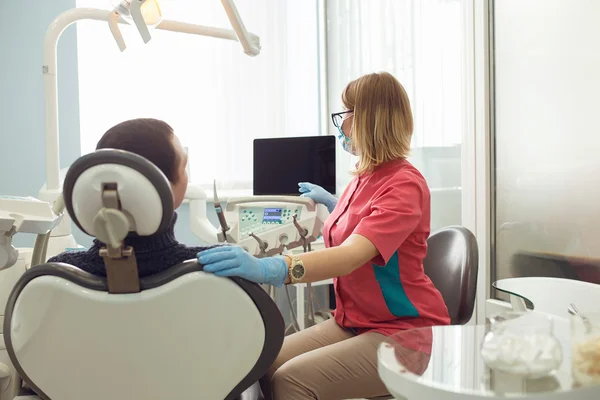 Zahnarzt zeigt einen Patienten röntgen. Zahnpflegekonzept. Zahnärztliche Untersuchung wird dem schönen Mann gegeben, der von Zahnarzt und seiner Assistentin umgeben ist — Stockfoto