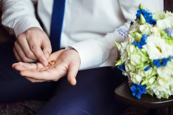 Anillos de boda en la mano del novio cerca del ramo de bodas —  Fotos de Stock