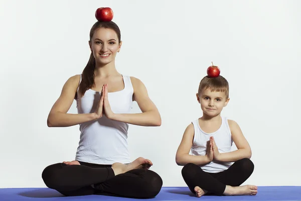 Madre e hijo haciendo yoga (ejercicios deportivos), divertirse y pasar un buen rato juntos. aislado en blanco. el concepto de un estilo de vida saludable — Foto de Stock