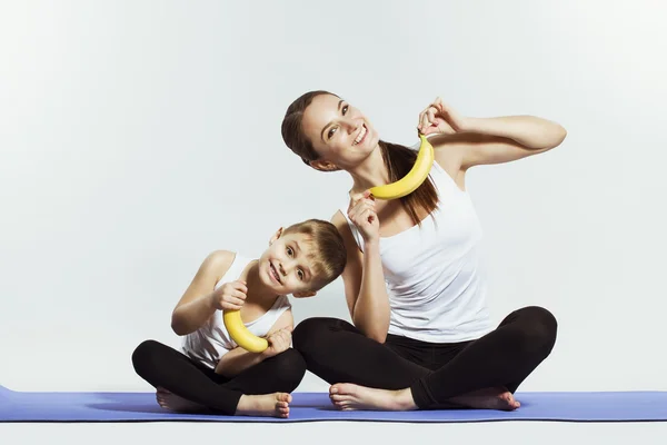 Mãe e filho fazendo ioga (exercícios esportivos), se divertir e passar um bom tempo juntos. isolado em branco. o conceito de um estilo de vida saudável — Fotografia de Stock