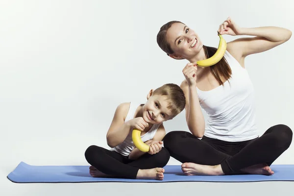 Mãe e filho fazendo ioga (exercícios esportivos), se divertir e passar um bom tempo juntos. isolado em branco. o conceito de um estilo de vida saudável — Fotografia de Stock