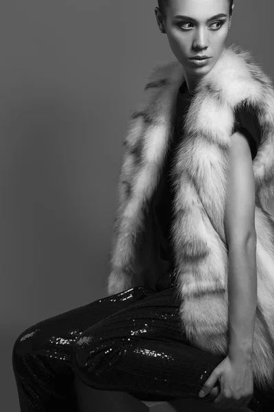 Σέξι κορίτσι ομορφιά με φυσικό μακιγιάζ. Μόδα μελαχρινή πορτραίτο ενός κοριτσιού ντυμένο με γούνινο παλτό και μαύρο πουκάμισο που ποζάρει σε γκρίζο φόντο. Ρετρό στυλ — Φωτογραφία Αρχείου