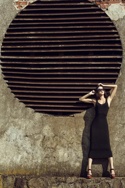 Retrato de moda de joven chica morena hermosa en vestido negro sexy y gafas de sol. Un disparo al aire libre. Estilo urbano —  Fotos de Stock