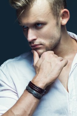 Male beauty concept. Portrait of fashionable hipster young man with stylish haircut posing over grey background. Perfect hair & skin. Tough guy. Vogue style. Close up. Studio shot