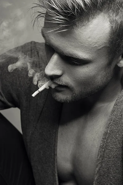 Portrait émotionnel d'un jeune modèle à la mode fumant une cigarette. Style rétro. Ferme là. Studio noir et blanc tourné . — Photo