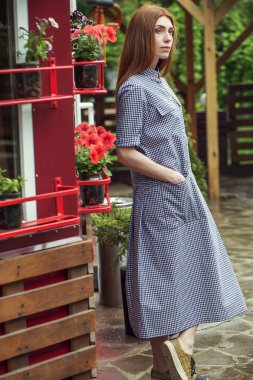 Güzel şık genç kız rahat kıyafetler (elbise ve spor ayakkabı) giyinmiş yağmur sonrası kentin sokaklarında yürüyor. Kadınlar için moda giyim kavramı