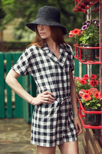 Hermosa joven elegante vestida con ropa casual (vestido y zapatillas de deporte) camina por las calles de la ciudad después de la lluvia. el concepto de ropa de moda para las mujeres — Foto de Stock