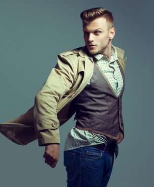 Trendy moda giyim ve ceket, gri arka plan üzerinde hareket poz çekici adam portresi. Stüdyo vurdu. Çok güçlü ve şık bir adam