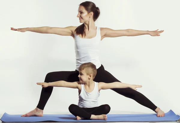 Madre e figlio fare yoga (esercizi sportivi), divertirsi e trascorrere un buon tempo insieme. isolato su bianco. il concetto di uno stile di vita sano — Foto Stock