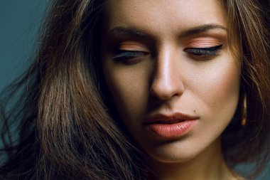 Şık bir model gri arka plan üzerinde poz kıvırcık saç ve natuure makyaj ile duygusal portre.