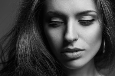 Şık bir model makyajlı gri arka plan üzerinde poz kıvırcık saç ve doğa duygusal portresi. Mükemmel sağlıklı cilt.