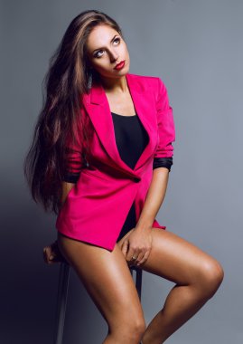 Duygusal bir muhteşem moda model gri arka plan üzerinde kırmızı ceket ve beden forması poz portresi.
