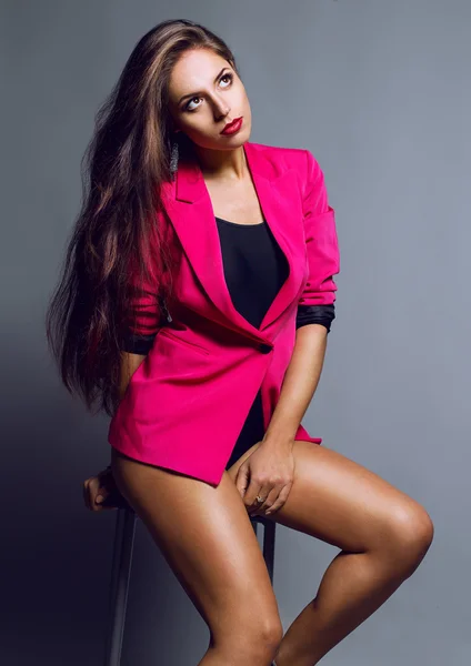 Emotional portrait of a gorgeous fashion model posing in red jacket and body shirt over gray background. — Stock Photo, Image