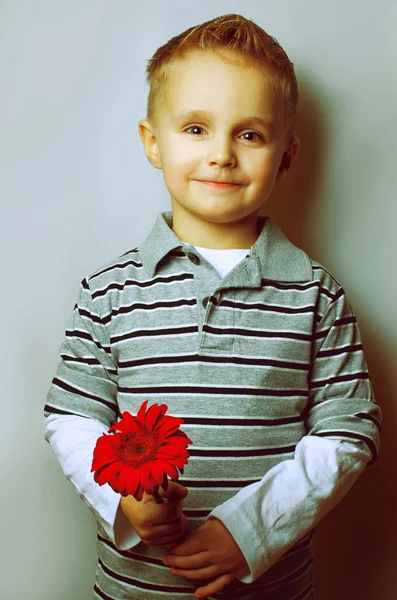 Emotionales Porträt eines gutaussehenden Jungen mit Blume in den Händen. perfekte Frisur. — Stockfoto