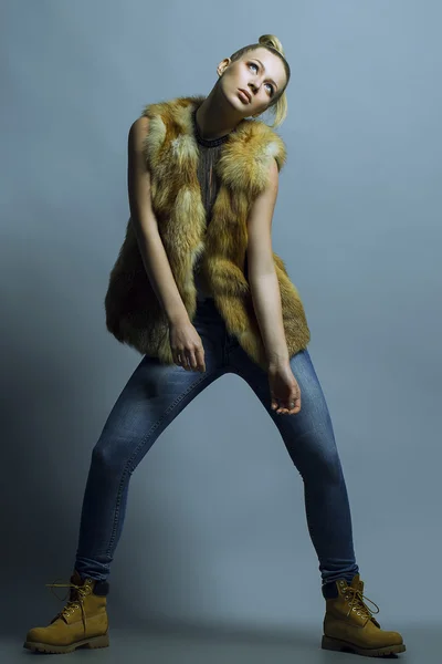 Känslomässiga porträtt av en vacker blond fotomodell i blå jeans och casual väst poserar på blå bakgrund. Studio skott. Hipster style. Kopiera utrymme — Stockfoto