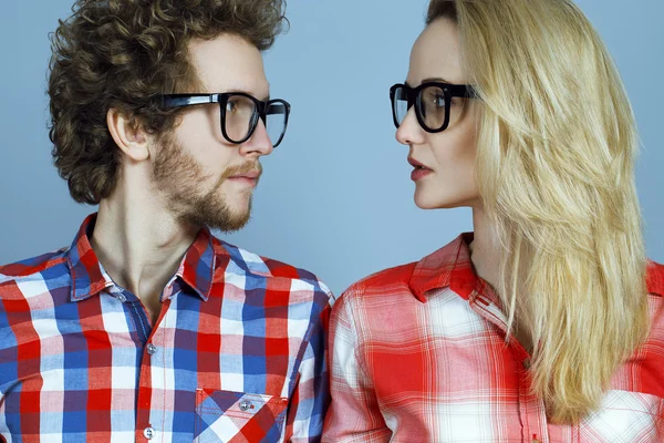 Portret van prachtige blonde mode man en vrouw (paar) in casual shirt dragen trendy bril die zich voordeed op blauwe achtergrond. Perfecte huid en kapsel. Vogue stijl. Close-up. Brillen concept — Stockfoto