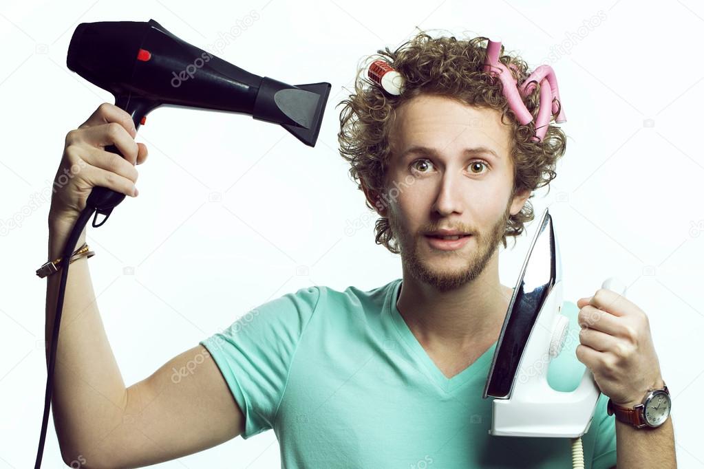 Funny  portrait of a young professional stylist with a hairdryer and iron in hands over a white background. the concept of female beauty in man's performance