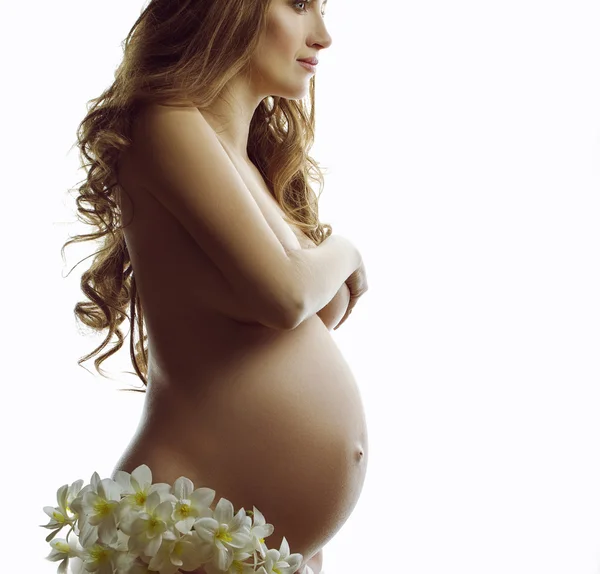 Donna incinta che tiene un fiore di giglio vicino alla linea dell'addome. Concetto del perfetto, l'amore e il bene incinta di donna. Bella donna incinta con lunghi capelli rossi, occhi blu e pelle perfetta — Foto Stock