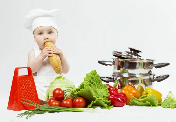 Piccolo Chef ragazzo preparare cibo sano e mangiare una pagnotta di pane su sfondo bianco. il concetto di vegetarianismo — Foto Stock