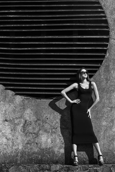 Fashion portrait of young beautiful brunette girl in sexy black  dresss and sunglasses. Vogue style. Outdoor shot.  Urban style — Stock Photo, Image