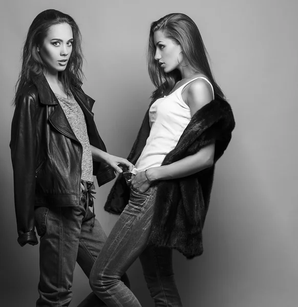 Fashion shot of two elegant beautiful girls (brunette and blonde) in studio on grey background, dressed in casual clothes . Shopping inspiration. Monochrome (black and white)  photo — 图库照片