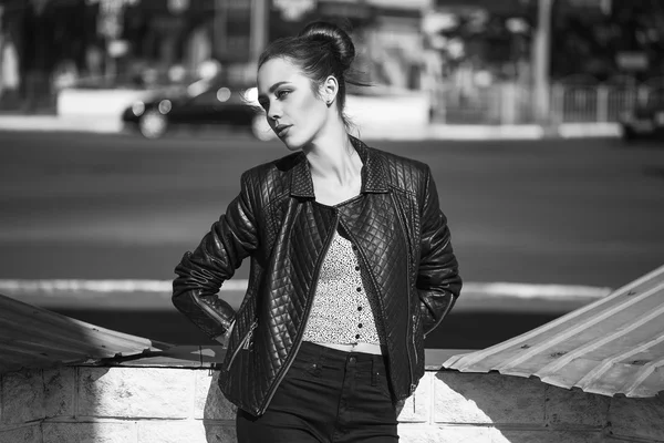 Female beauty concept. Portrait of fashionable young girl in casual black jeans, black jacket, white crop-top, sunglasses and small  bag posing on the street. Perfect hair & skin. Vogue style. outdoor shot — Stock Photo, Image