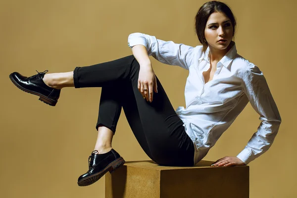 Concept de beauté féminine. Portrait de jeune fille à la mode en vêtements classiques posant sur fond d'or. Cheveux et peau parfaits. Style vogue. Plan studio — Photo