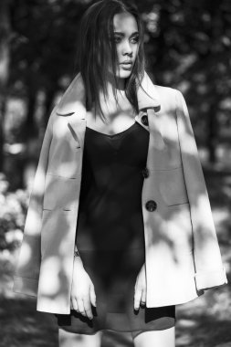 Kadın güzellik kavramı. Şık genç kız portresi hafif bir palto ve vahşi doğa üzerinde poz Siyah şeffaf elbise giymiş. Mükemmel saç ve cilt. Vogue tarzı. Açık atış