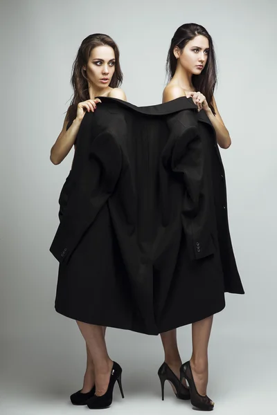 Foto de moda de duas belas meninas morenas elegantes em estúdio em fundo cinza, vestidas com casaco masculino e sapatos pretos clássicos. Inspiração de compras . — Fotografia de Stock
