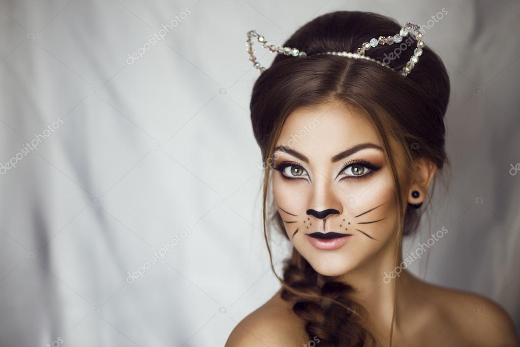 Sexy beauté fille avec chat de maquillage sur le visage et les oreilles sur sa tête. Provocateur Make up. Luxe femme aux yeux verts.