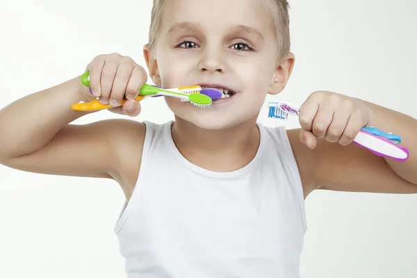 Criança feliz e limpo lavar os dentes vestindo em camisa curta branco isolado. Feche o retrato de um menino com escovas de dentes coloridas — Fotografia de Stock