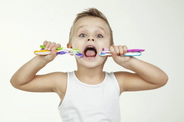 Happy and clean kid washing teeth wearing in white short shirt- isolated. Close up portrait of a little boy with color toothbrushes