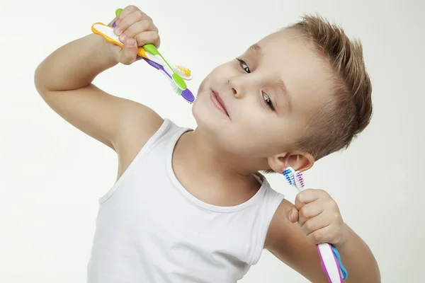 Criança feliz e limpo lavar os dentes vestindo em camisa curta branco isolado. Feche o retrato de um menino com escovas de dentes coloridas — Fotografia de Stock