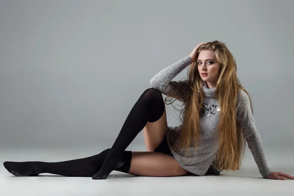 Female beauty concept. Portrait of fashionable young girl in black (socks) tights, a classic warm sweater over gray background. Vogue style. Studio shot. Black and white photo — Stock Photo, Image