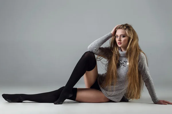 Concept de beauté féminine. Portrait de jeune fille à la mode en collants noirs (chaussettes), un pull chaud classique sur fond gris. Style vogue. Prise de vue. Photo noir et blanc — Photo