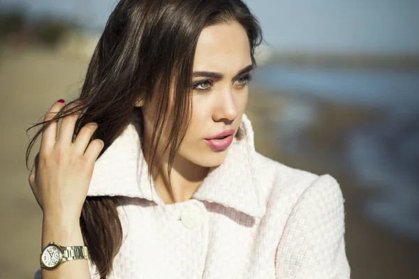 Concetto di alta moda. Ritratto emotivo di bella bruna con i capelli lunghi e trucco perfetto, indossando in cappotto rosa. il tempo soleggiato sulla spiaggia. Stile italiano di lusso. Colpo esterno — Foto Stock